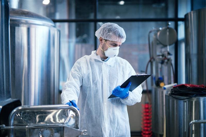 industrial worker white protective clothes holding checklist reading results
